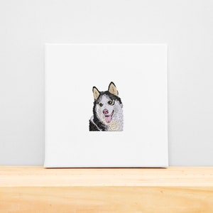 May include: Embroidered image of a black and white husky dog with a pink tongue sticking out. The dog is looking directly at the viewer.