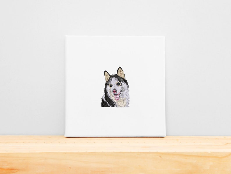 May include: Embroidered image of a black and white husky dog with a pink tongue sticking out. The dog is looking directly at the viewer.
