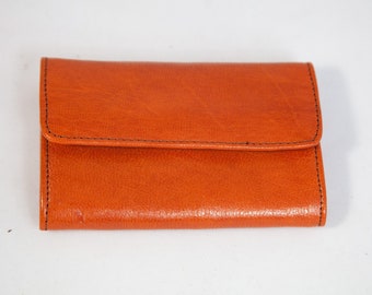 May include: A small, orange leather wallet with a fold-over flap.