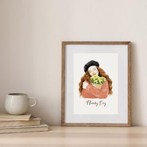 May include: Watercolor art print in a wooden frame. The artwork depicts a person with long auburn hair and a black beret, holding a bouquet of yellow flowers. The text "Flowery Day" is written below the illustration.