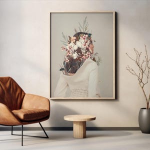 以下が含まれることがあります： 女性の頭から花が咲いている絵画の額縁。女性は白いドレスを着て、横を向いている。背景は薄いグレーの色です。