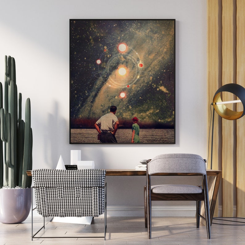 May include: A framed print of a surrealist collage featuring two figures standing in a field, looking up at a starry sky with a glowing sun and planets. The sky is a dark blue with a swirling galaxy in the background.
