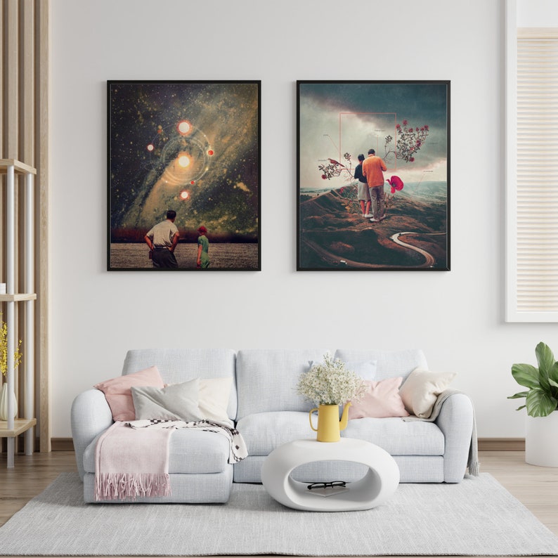 May include: Two framed art prints, one depicting a couple walking on a winding path in a landscape with a red flower, and the other depicting a starry sky with a galaxy and planets. The prints are hanging on a white wall above a light gray sectional sofa with a pink throw blanket.