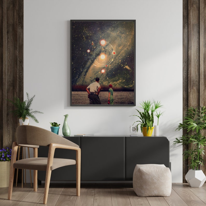 May include: A framed print of a surrealist collage featuring two figures standing in a field, looking up at a starry sky with multiple glowing orbs and a galaxy in the background.