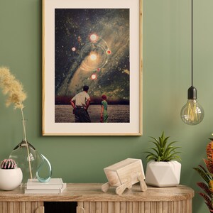 May include: A framed collage art print featuring a couple standing in a field, looking up at a starry night sky with a galaxy and planets. The print has a vintage aesthetic.