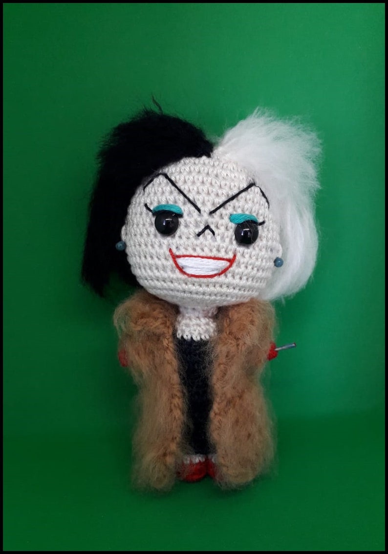 Op de afbeelding: Een gehaakte pop van Cruella de Vil uit de Disney-film 101 Dalmati&euml;rs. De pop heeft zwart en wit haar, een rode glimlach en draagt een bruine bontjas.