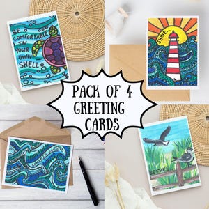 May include: A pack of four greeting cards with hand-drawn illustrations. The cards feature a turtle, a lighthouse, ocean waves, and birds. Each card has a unique design with inspirational text. Includes envelopes.