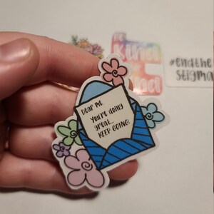 May include: A blue and white envelope sticker with the text "Dear me. You're doing great... KEEP GOING!" surrounded by pink, green, and purple flowers.