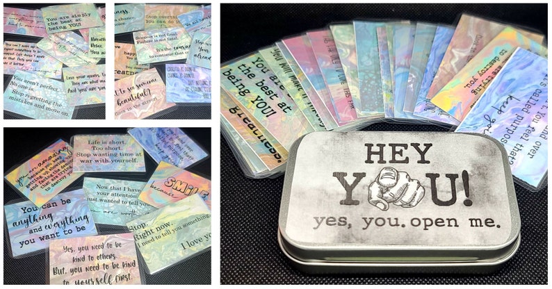 May include: A silver tin with the words "HEY YOU! yes, you. open me." printed on it. The tin contains a set of colorful cards with positive affirmations, such as "You are the best at being YOU!" and "Life is short. Too short. Stop wasting time at war with yourself."