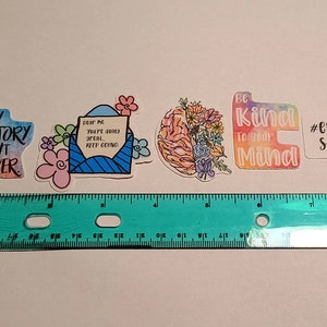 May include: Four colorful stickers with positive messages. The first sticker is a watercolor design with a semicolon and the text "My story isn't over". The second sticker is a blue envelope with a white heart and the text "Dear me, you're doing great... keep going!". The third sticker is a brain with flowers and the text "Be kind to your mind". The fourth sticker is a white sticker with the text "#endthe stigma".