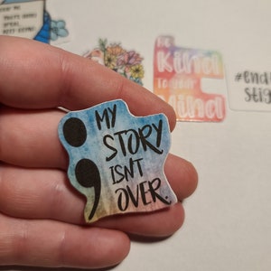 May include: A rainbow-colored sticker with a black semicolon and the text "My story isn't over."
