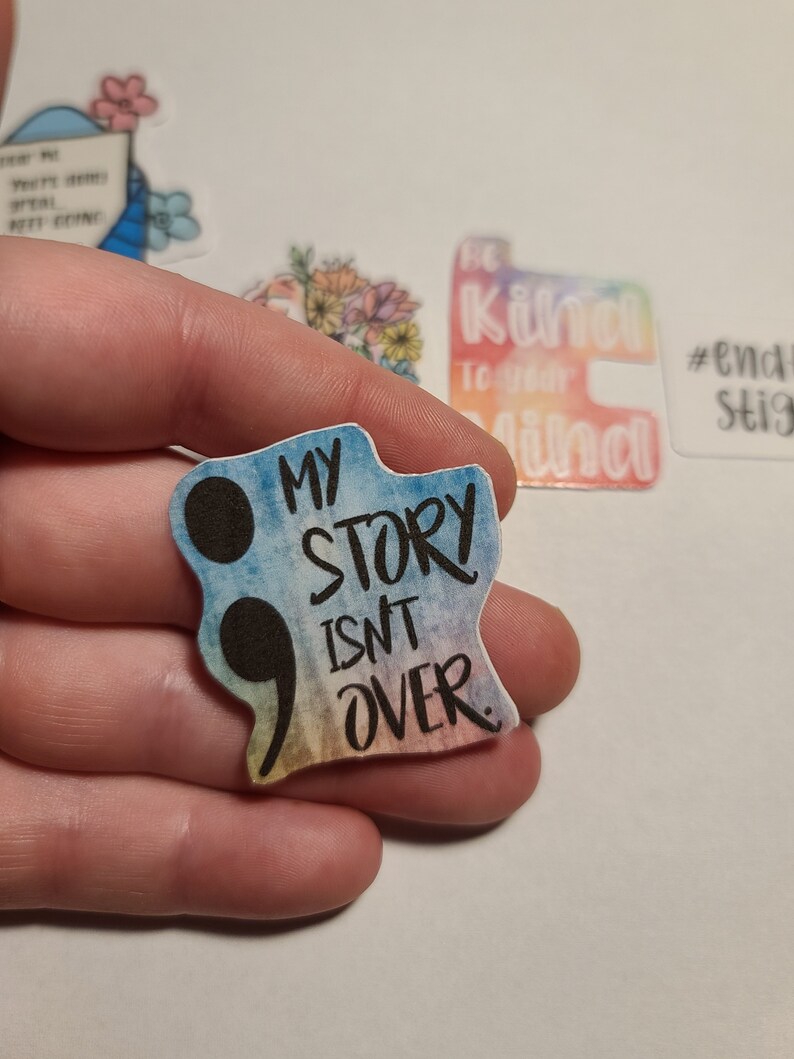May include: A rainbow-colored sticker with a black semicolon and the text "My story isn't over."