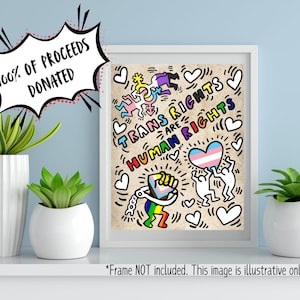 May include: A white framed print with a colorful illustration of stick figures holding hands and hearts. The text "Trans Rights Are Human Rights" is written in rainbow colors. The print is on a white background and has a white border.