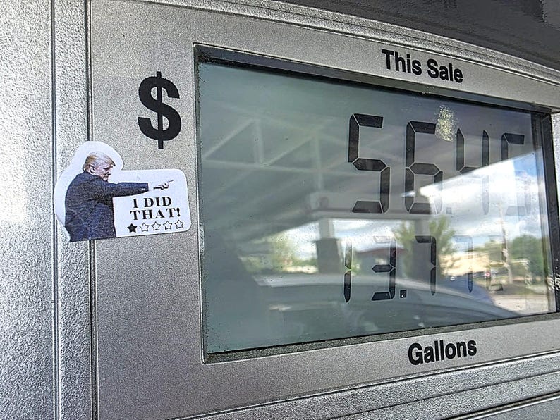 K&ouml;nnte beinhalten: Eine Tankstellenanzeige zeigt einen Preis von 56,46 Dollar und 13,7 Gallonen an. Auf der Pumpe befindet sich ein Aufkleber eines Mannes, der mit dem Text "I DID THAT!" zeigt.