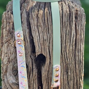 May include: A mint green dog collar and leash set. The collar and leash are made of a smooth material with gold-colored hardware. The leash has a floral patterned section. The collar has a matching floral pattern on the inside.