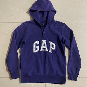 Peut inclure: Un sweat à capuche violet avec un logo "GAP" brodé en blanc sur le devant.