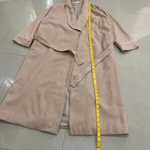 K&ouml;nnte beinhalten: Beigefarbener Bademantel mit wei&szlig;er Paspelierung und passendem G&uuml;rtel. Der Bademantel hat eine Tasche mit gesticktem Logo. Die L&auml;nge des Bademantels betr&auml;gt ca. 132 cm.