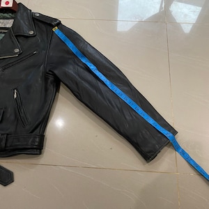 May include: Black leather motorcycle jacket with a zipper closure and a blue measuring tape showing the sleeve length is 28 inches.