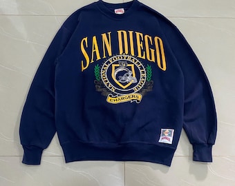 Puede incluir: Sudadera azul marino de los San Diego Chargers. La sudadera presenta las palabras "SAN DIEGO" en letras amarillas arqueadas sobre un emblema circular con un casco de fútbol y las palabras "NATIONAL FOOTBALL LEAGUE CHARGERS".
