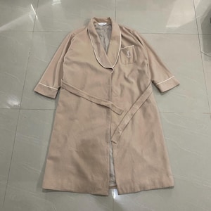 K&ouml;nnte beinhalten: Beiger Bademantel mit wei&szlig;er Paspelierung an Kragen, Manschetten und Tasche. Der Bademantel hat einen passenden G&uuml;rtel und ein kleines gesticktes Logo auf der Tasche. Der Bademantel ist aus weichem, leichtem Stoff.