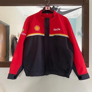 May include: A red and black jacket with a Shell logo and the text "Helix" on the front. The jacket has a zipper closure and a drawstring at the waist.