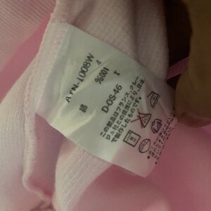 Puede incluir: Una etiqueta blanca con texto negro unida a una prenda rosa. La etiqueta dice "ATN-1008W", "Algod&oacute;n 4%", "D-OS-46", y "Este producto fue fabricado en Jap&oacute;n en colaboraci&oacute;n con la empresa francesa "Creations", y est&aacute; hecho con materiales provenientes de Francia. No lo deje en remojo en agua durante largos per&iacute;odos de tiempo."