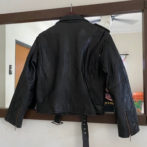 May include: Black leather jacket with a belt and zippered cuffs. The jacket has a classic biker style.