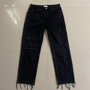 Puede incluir: Vaqueros negros desgastados de denim con dobladillos deshilachados.