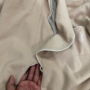 K&ouml;nnte beinhalten: Ein beiger Bademantel mit wei&szlig;er Paspelierung und einer Tasche mit Logo. Der Bademantel ist aus einem weichen Material gefertigt und hat eine lockere Passform. Der Bademantel ist auf Komfort und Entspannung ausgelegt.