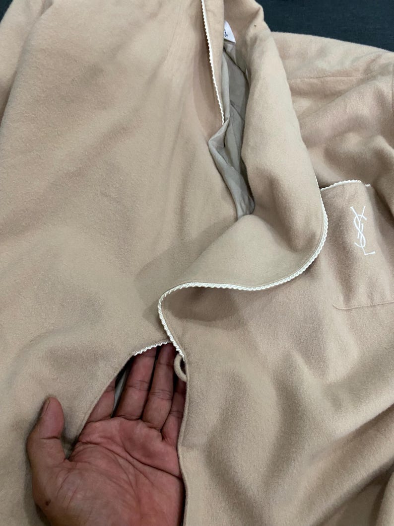 K&ouml;nnte beinhalten: Ein beiger Bademantel mit wei&szlig;er Paspelierung und einer Tasche mit Logo. Der Bademantel ist aus einem weichen Material gefertigt und hat eine lockere Passform. Der Bademantel ist auf Komfort und Entspannung ausgelegt.