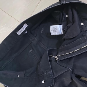 Puede incluir: Vaqueros de mezclilla negros con cierre de cremallera y una etiqueta blanca que dice "A.L.C.  MADE IN USA  26"