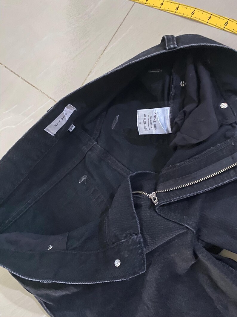 Puede incluir: Vaqueros de mezclilla negros con cierre de cremallera y una etiqueta blanca que dice "A.L.C.  MADE IN USA  26"