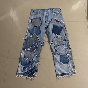 Op de afbeelding: Lichtblauwe spijkerbroek met een patchwork-ontwerp bestaande uit verschillende denim patches in blauwtinten. De patches zijn op de jeans genaaid. De jeans hebben een gerafelde zoom en een klassiek vijf-zakken ontwerp.