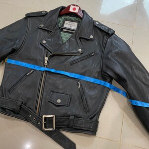May include: Black leather motorcycle jacket with a zipper closure, a belt, and multiple pockets. The jacket has a label that reads "First Class Leatherwear" and a size tag that reads "Size 40".