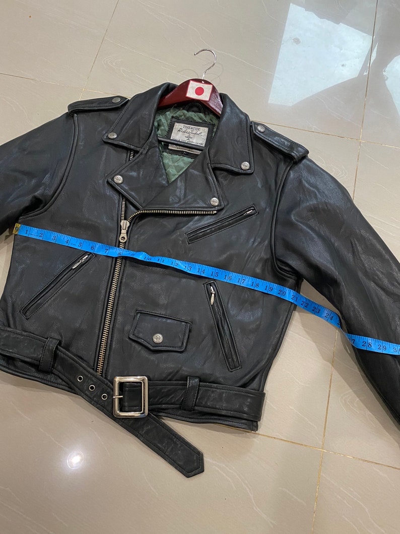 May include: Black leather motorcycle jacket with a zipper closure, a belt, and multiple pockets. The jacket has a label that reads "First Class Leatherwear" and a size tag that reads "Size 40".