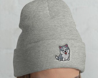 Könnte beinhalten: Eine graue Mütze mit einem niedlichen Husky-Cartoon, der auf der Vorderseite gestickt ist. Die Mütze ist aus einem weichen, bequemen Material gefertigt und perfekt, um den Kopf im Winter warm zu halten.