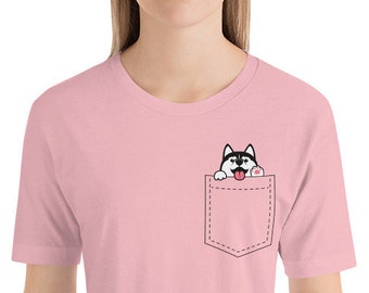 May include: A pink t-shirt with a front pocket featuring a black and white husky dog peeking out with its tongue sticking out.