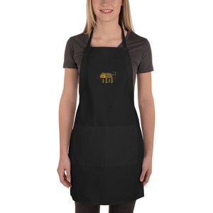 May include: Black apron with a monkey design embroidered on the front. The apron has a large pocket on the front.