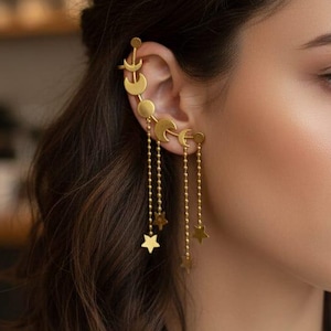May include: Gold-toned ear cuff featuring crescent moons and stars. The ear cuff is designed to climb up the ear, with dangling star charms suspended from delicate chains. A stylish celestial-themed accessory.