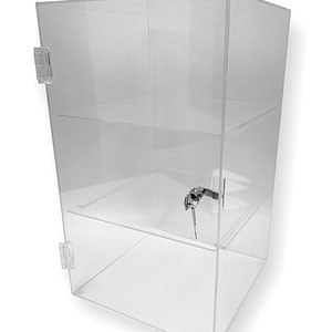 May include: Clear acrylic display case with a hinged door and a lock. The case has two shelves and is designed to showcase items. The transparent design allows for full visibility of the contents. The case is suitable for retail or personal display.