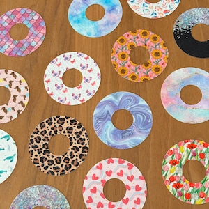 Puede incluir: Surtido de 12 pegatinas redondas coloridas y estampadas con un agujero en el centro. Las pegatinas presentan varios diseños, incluyendo mariposas, girasoles, corazones y patrones de mármol.