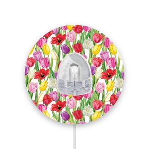 May include: A round white mouse mat with a colourful floral design featuring tulips in shades of red, pink, yellow, and purple. The mouse mat has a hole in the centre for a mouse.