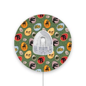 May include: A round wireless mouse with a green background featuring a repeating pattern of dinosaurs, eggs, and mosquitos.