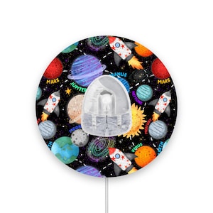 May include: A round, black and white nightlight with a space theme. It features planets, stars, rockets, and the words "Mars", "Jupiter", "Uranus", "Neptune", "Mercury", "Earth", "Venus", and "Moon".