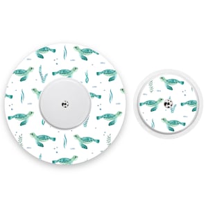 May include: Two round, white medical device covers with a repeating pattern of green sea turtles swimming in a blue ocean. The larger cover is 7.6 cm in diameter and the smaller cover is 3.8 cm in diameter.