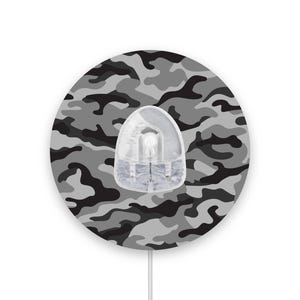 Può includere: Un tappetino per mouse rotondo e bianco con un motivo mimetico nero e grigio. Il tappetino per mouse ha un mouse in plastica trasparente con un cavo bianco.