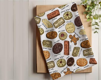 May include: White tea towel with a colorful illustration of various biscuits and cookies. The names of each biscuit are printed on the tea towel, including Bourbon, Rich Tea, Ginger Parkin, Custard Cream, and Digestive.