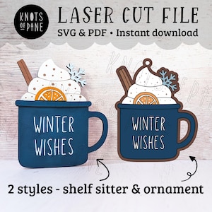 Peut inclure: Fichier de découpe laser pour une décoration de tasse de chocolat chaud sur le thème de l'hiver. La tasse est bleue avec une inscription blanche qui dit "Winter Wishes". La décoration est ornée d'une crème fouettée blanche, d'un bâton de cannelle brun et d'une tranche d'orange.