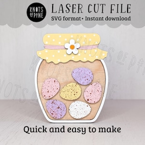 May include: A wooden laser cut file of a jar with a lid and six speckled eggs inside. The lid is yellow with white polka dots and a daisy. The text "LASER CUT FILE" and "Quick and easy to make" are visible.