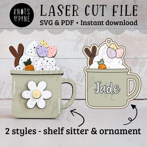 May include: Laser cut file for a hot chocolate mug with bunny ears and Easter eggs. The mug is green and has a white daisy on the side. The file includes two styles: a shelf sitter and an ornament. The text "Jade" is written on the mug.